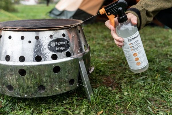 Gratar Atago Petromax pe iarba si persoana care pulverizeaza solutie de curatare
